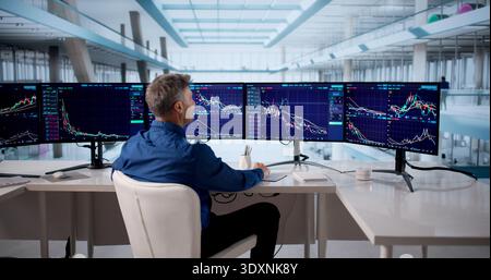 Senior Stock Broker Analyzing Market Data On Multiple Computer Screens. Stock Photo