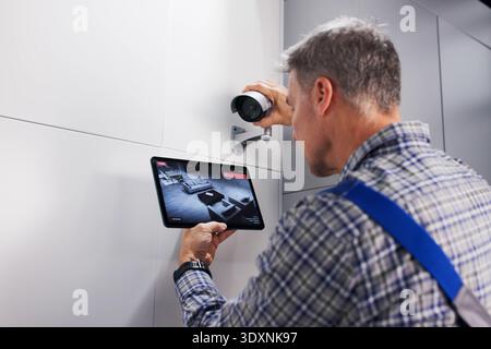 Skilled Technician Installs Secure CCTV Surveillance Camera Alarm System Professionally. Stock Photo