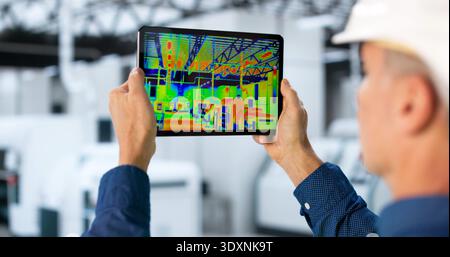 Male Engineer Using Thermal Camera In Factory For Inspection Of Insulation. Stock Photo