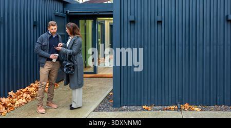 Couple discussing modular home made with shipping containers real estate options using smartphone Stock Photo