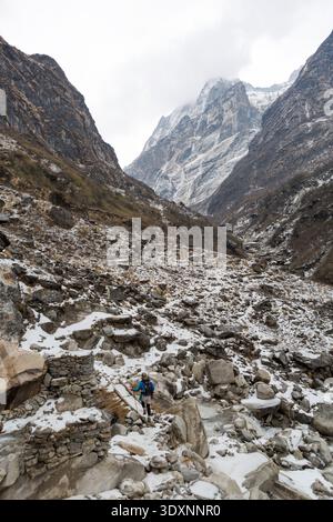 A trekker crosses a small wooden bridge over a rocky stream on the trail through the Modi Khola valley near Hinko, Nepal. Stock Photo