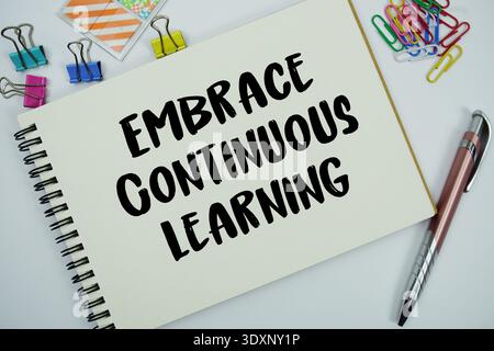 Embrace Continuous Learning text message written on notepad with stationery flat lay on white background Stock Photo