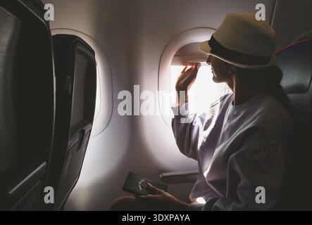 Close up caucasian flight passenger sit by window opens window cover on arrival cabin view Stock Photo