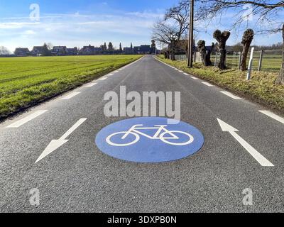 Large marking on narrow district road country road in rural area painted symbol for road signs 244.1-40 beginning end of a bicycle road, next to it di Stock Photo