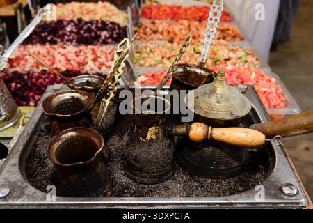 A collection of blackened metal pots with wood handles called a cezve in Turkish or an ibrik in Arabic which are used for brewing Turkish coffee at a Stock Photo