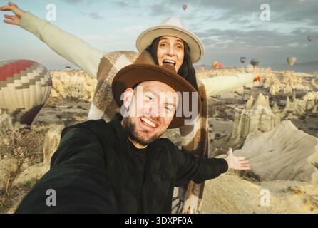 Close up Couple of tourists having fun watching hot air balloons from viewpoint smile to camera in Cappadocia at holiday - Happy friends laughing toge Stock Photo
