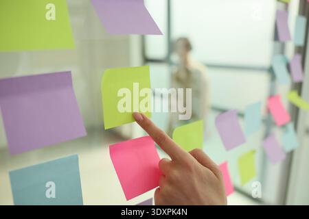 Colorful sticky notes adorn the office wall as a team brainstorms creative ideas for a project during a bright morning meeting Stock Photo