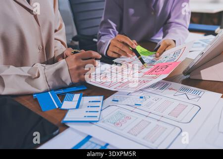 Close up ux developer and ui designer brainstorming about mobile app interface wireframe design on table with customer breif and color code at modern Stock Photo