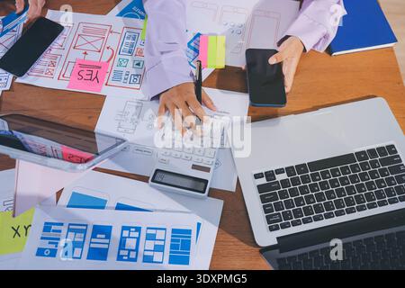 Close up ux developer and ui designer brainstorming about mobile app interface wireframe design on table with customer breif and color code at modern Stock Photo