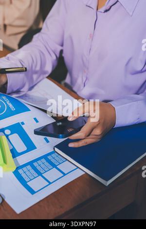 Close up ux developer and ui designer brainstorming about mobile app interface wireframe design on table with customer breif and color code at modern Stock Photo