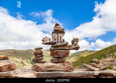 Stacked balanced stones creating cairns on a mountain wall under a blue sky, symbolizing harmony and peace Stock Photo