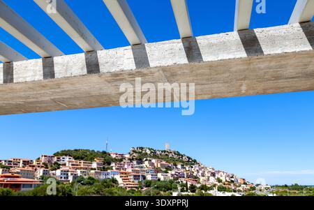 historic Sardinian village framed by an infrastructure of white concrete beams under construction isolated in front of the blue summer sky Stock Photo
