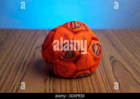Basra, Iraq- March 03, 2026: Orange Arsenal Football Soccer Ball with Printed Signatures on Table Stock Photo