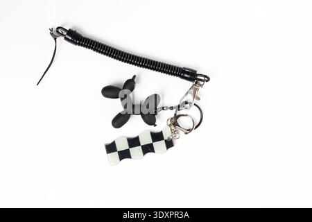Black and White Checkered Flag and Balloon Dog Keychains on White Background Stock Photo