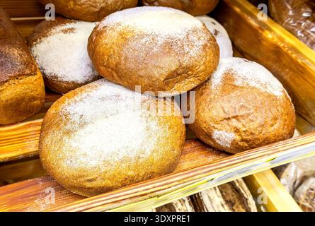 Freshly baked bread on the counter. Freshly baked  loaves of bread displayed on wooden shelves in bakery Stock Photo