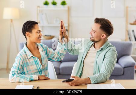 Woman and man students reaching agreement, giving high five to each other, working as friendly team Stock Photo