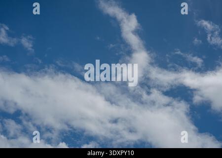 Wispy white clouds stretching diagonally across a blue sky Stock Photo