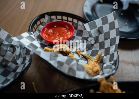 Empty black basket with checkered paper red sauce and food crumbs Stock Photo