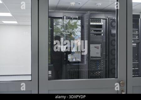 Technician inspecting servers through glass door in a modern data center server room Stock Photo