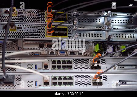 Server rack with network switches and connected fiber and ethernet cables in a data center hardware setup Stock Photo