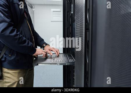 IT technician using rack console laptop to service servers in a data center server room Stock Photo