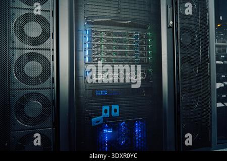 High-performance server rack in a data center with illuminated network equipment and cooling fans Stock Photo