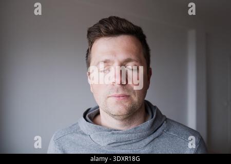 Serene middle aged Caucasian man standing with closed eyes, enjoying a peaceful moment  Stock Photo