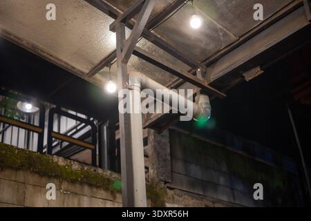PVC pipe and glowing light bulbs attached to a metal frame at night Stock Photo