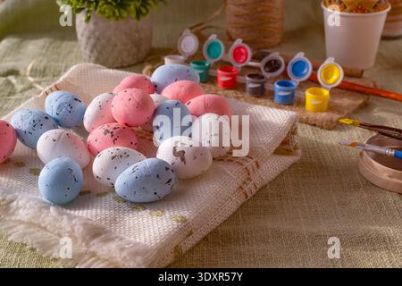 Pastel Easter eggs with painting supplies and brushes on rustic textile background spring holiday craft scene Stock Photo