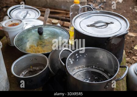 Aluminum cooking pots and a frying pan on dirt ground Stock Photo
