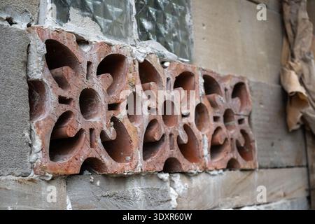 Red clay ventilation block set in a grey concrete wall Stock Photo