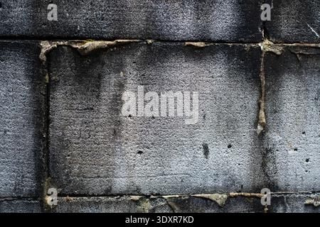 Close up of dark grey concrete blocks joined by messy mortar Stock Photo