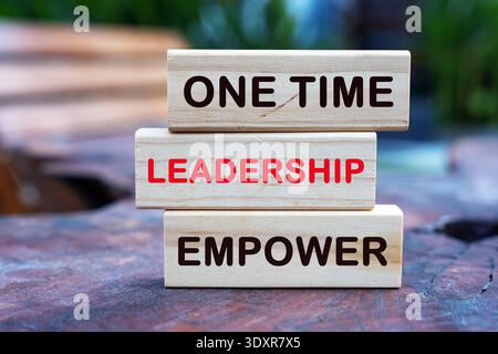 Wooden blocks stacked on a rustic wood surface with the text "ONE TIME LEADERSHIP EMPOWER". Concept for executive coaching. Stock Photo