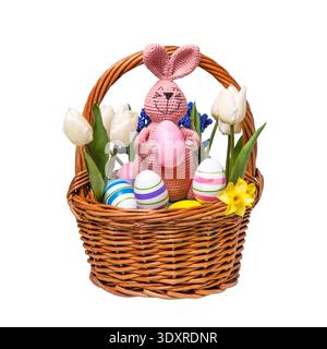Multicolored Easter eggs in a basket with spring flowers: blue muscari, yellow daffodils and white tulips and pink Easter knitted bunny with pink whit Stock Photo