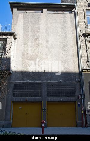 Industrial style grey facade with two bright yellow garage doors and a red fire hydrant in Budapest city center, Hungary Stock Photo