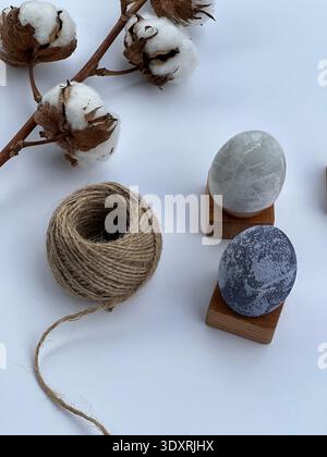 Minimalist Easter still life with decorative eggs, cotton branch and natural twine on white background, Scandinavian style spring holiday decor. Stock Photo