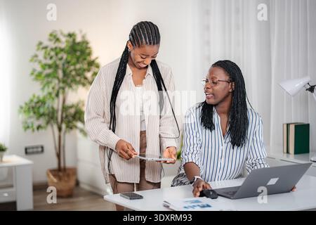 African businesswomen collaborating on digital project in home office Stock Photo