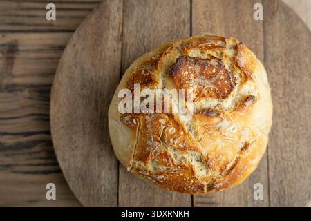 Overhead close-up of rustic sourdough boule on wooden board Stock Photo