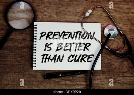 Prevention is Better Than Cure text written on notepad with stethoscope and magnifying glass on wooden background Stock Photo