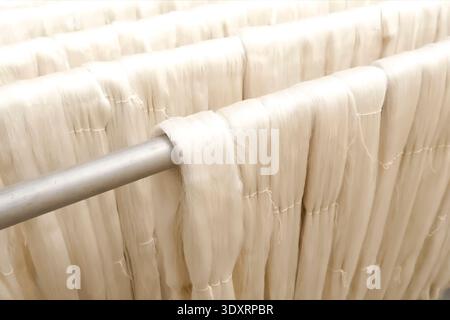 Hanging silk threads on wooden bars. Stock Photo