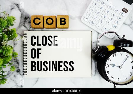 COB Close of Business text with calculator and alarm clock on marble background Stock Photo