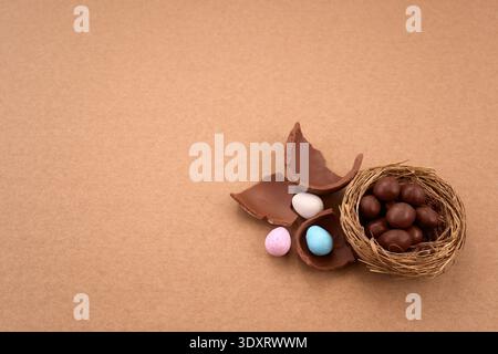 Chocolate easter eggs and nest with candy on brown background Stock Photo