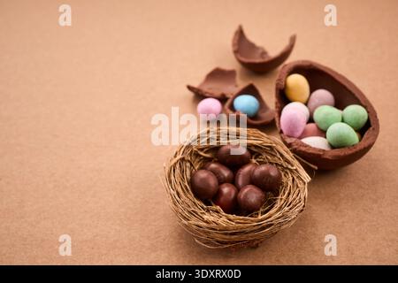 Chocolate easter eggs and nest with candy on brown background Stock Photo