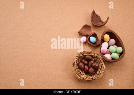 Chocolate easter eggs and candy scattered on brown background Stock Photo