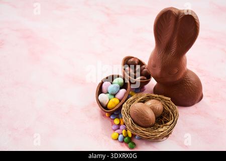 Chocolate bunny, easter eggs, and candies on pink surface Stock Photo