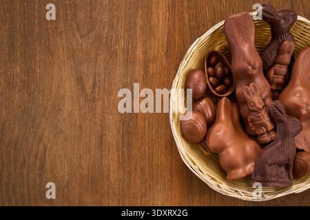 Chocolate easter bunnies and eggs in basket on wood Stock Photo