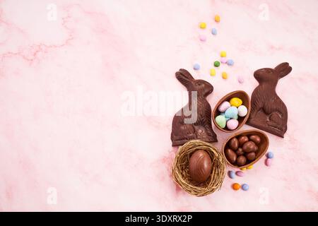 Easter chocolate bunnies, eggs, and candy on pink marble Stock Photo