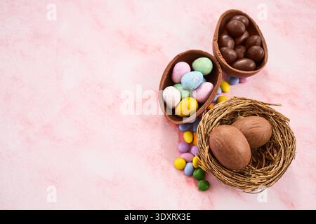 Easter chocolate eggs and candy in nest on pink background Stock Photo