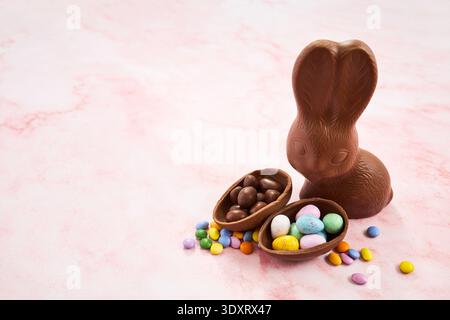 Chocolate easter bunny with candy eggs on pink marble Stock Photo