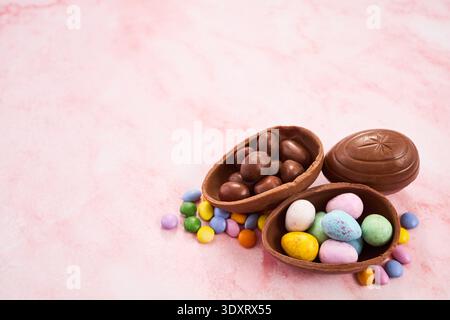 Easter chocolate egg candy spilling on pink background Stock Photo